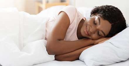 A woman smiling while awakening from sleep.