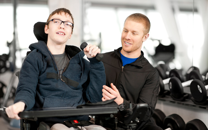 A physical therapist working with a young man in a wheelchair.