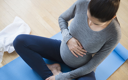Pregnant woman sitting on yoga mat.