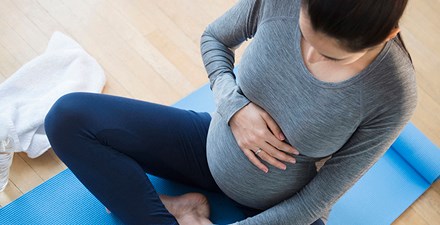 Pregnant woman sitting on yoga mat.
