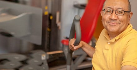 Roberto using strengthing equipment during physical therapy