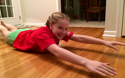 A child doing a "superman" exercise on the floor.