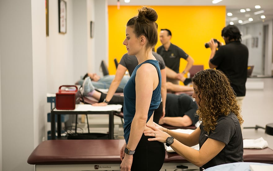 A physical therapist conducts an assessment of a woman's low back.