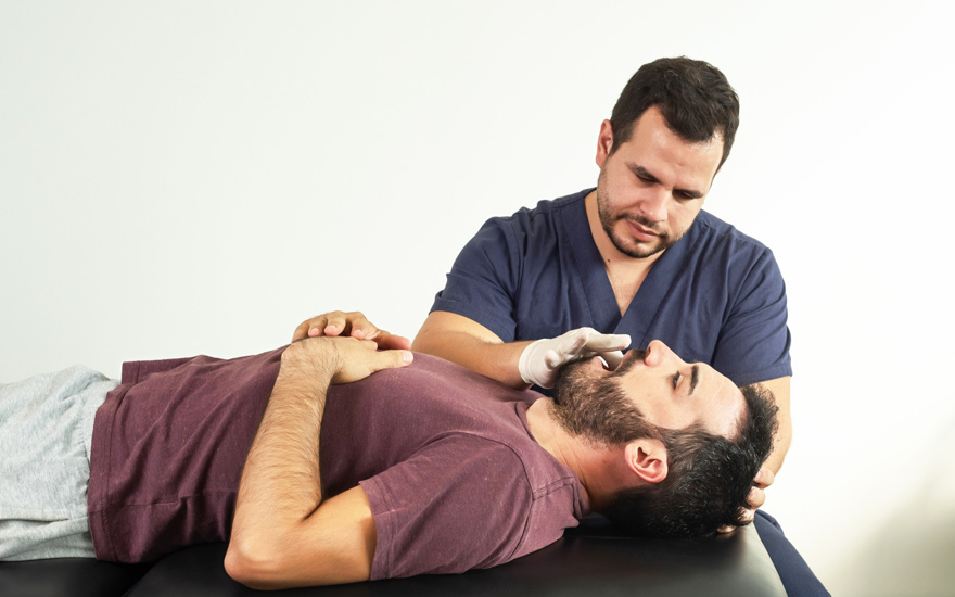 A physical therapist examines a person's jaw.