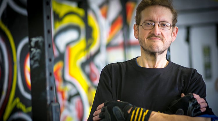 Scott standing in a gym in triumph after losing 300 pounds.