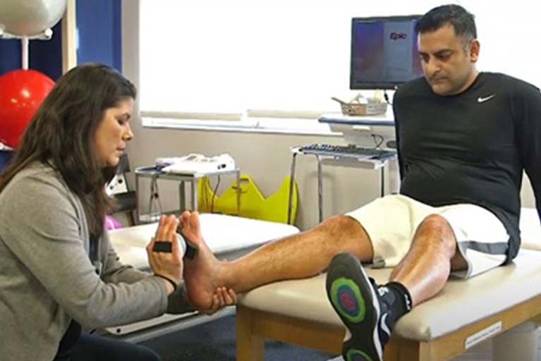 Physical therapist providing hands-on therapy for a man with an achilles injury.