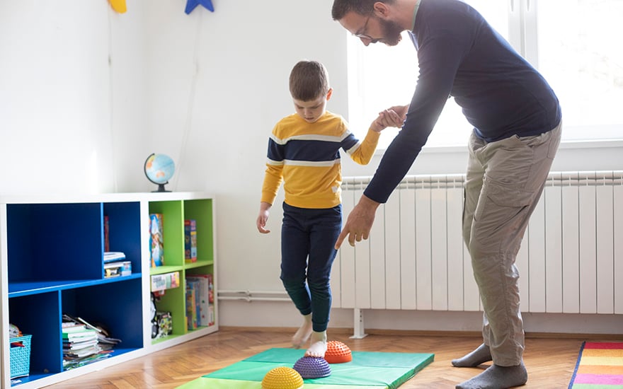 Physical therapist works on balance with a young boy