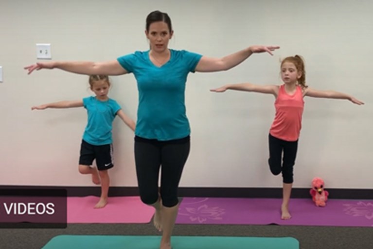 A physical therapist and two young volunteers demonstrate an imaginative yoga routine for kids pretending to take a trip to the zoo.