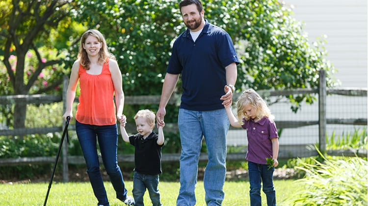 Laura, walking outdoors with her husband and two daughters