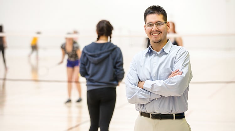 Gerardo, standing on a volleyball court with players in the background.