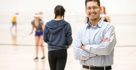 Gerardo, standing on a volleyball court with players in the background.