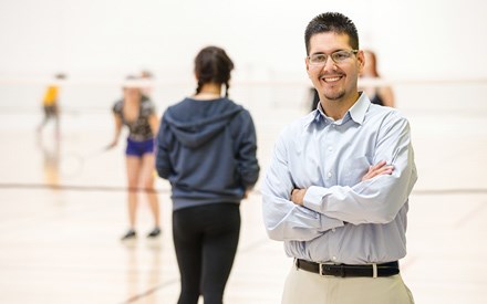 Gerardo, standing on a volleyball court with players in the background.