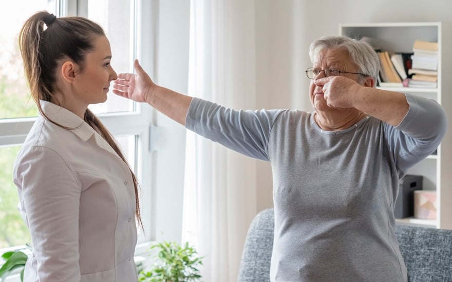 A physical therapist guides an older adult female in balance training.