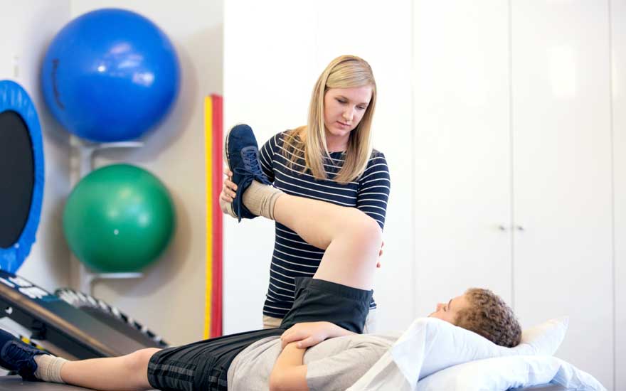 A physical therapist working with a young person with hypermobile joints.