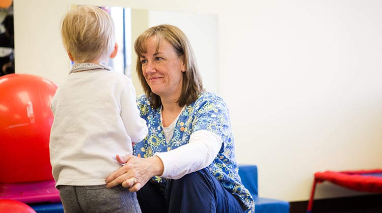 A physical therapist working with a young child