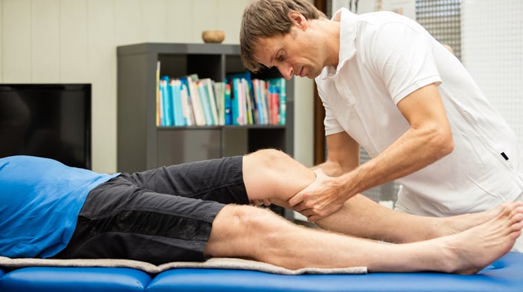 A physical therapist provides hands-on treatment on a patient's leg.