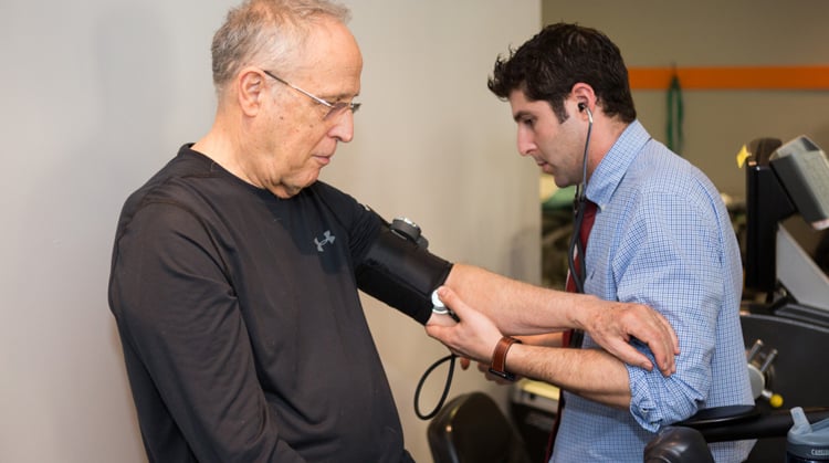 A physical therapist monitors vital signs of a patient during therapy