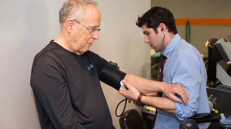 A physical therapist monitors vital signs of a patient during therapy