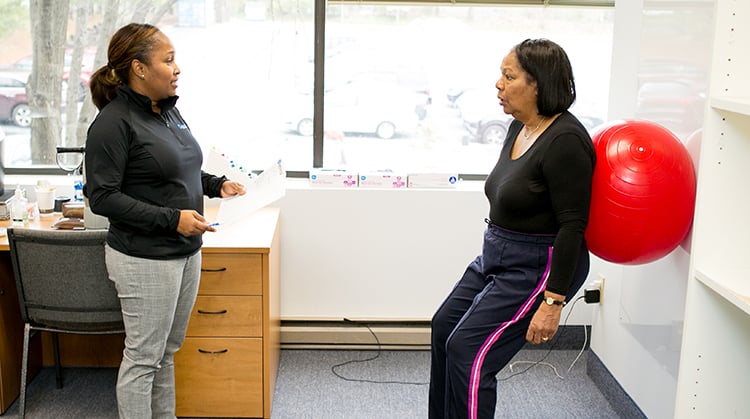 A physical therapist working with a woman on muscle strengthening exercises