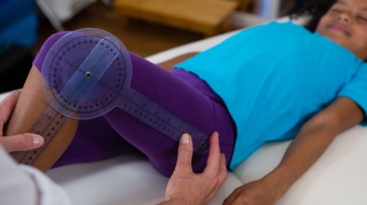 A physical therapist using a goniometer to measure a child's leg