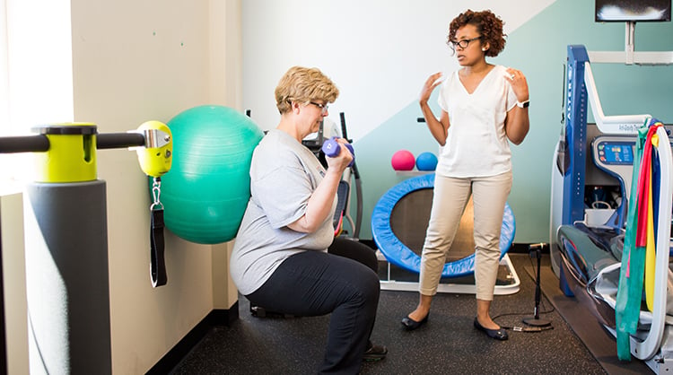 A physical therapist leads a patient through strengthening exercises