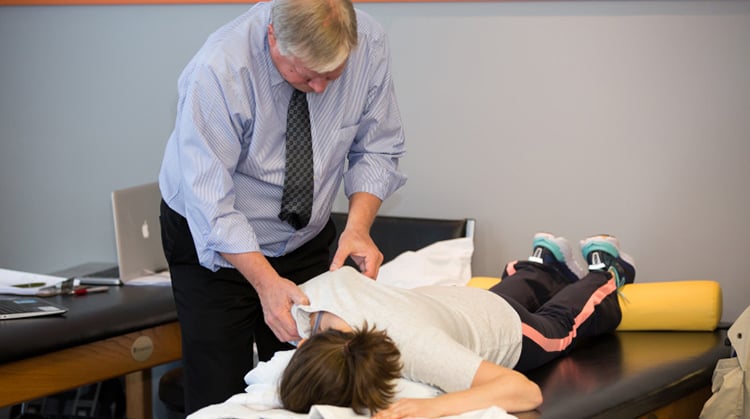 A physical therapist uses hands-on therapy on a person's shoulder blade
