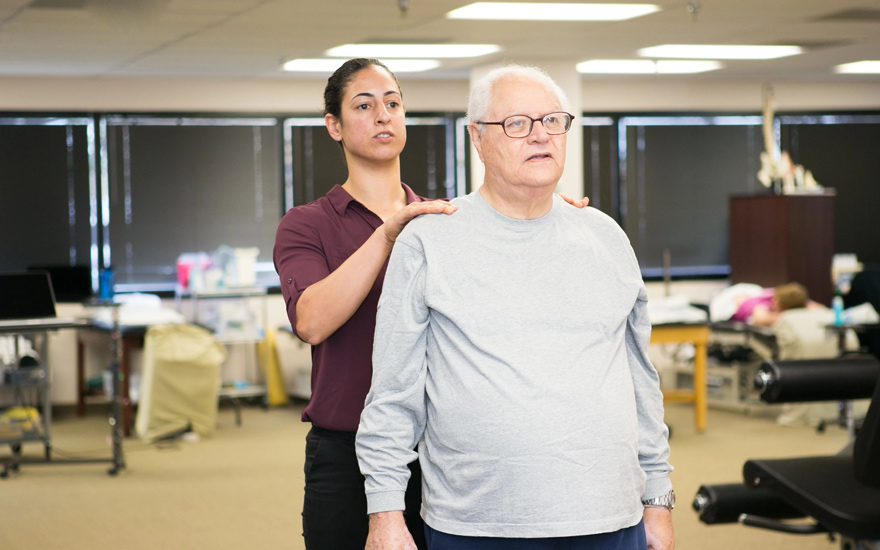 A physical therapist helps an older adult with postural training.