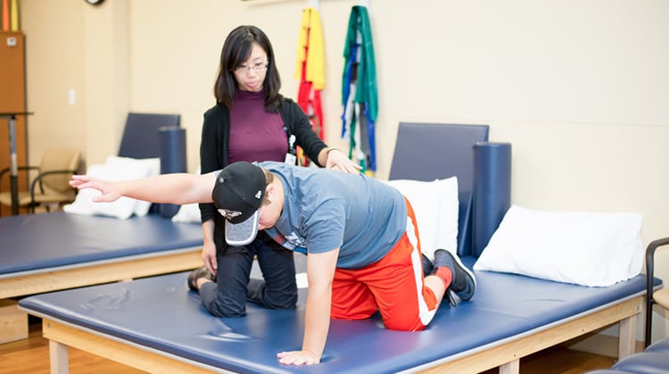 A physical therapist working with a young athlete on core strengthening