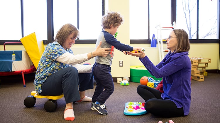 A physical therapist working with a child on mobility