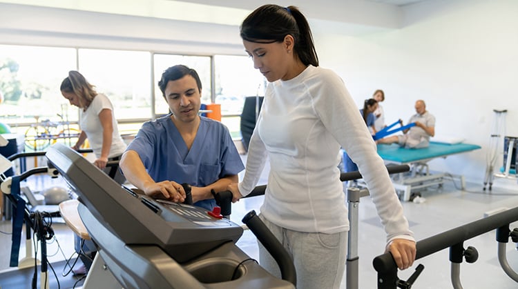 A physical therapist working with a patient on a treadmill