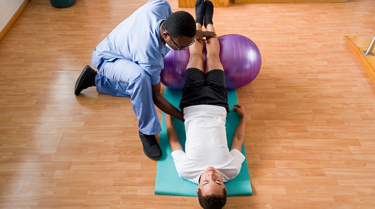 A physical therapist works with a patient on strengthening exercises