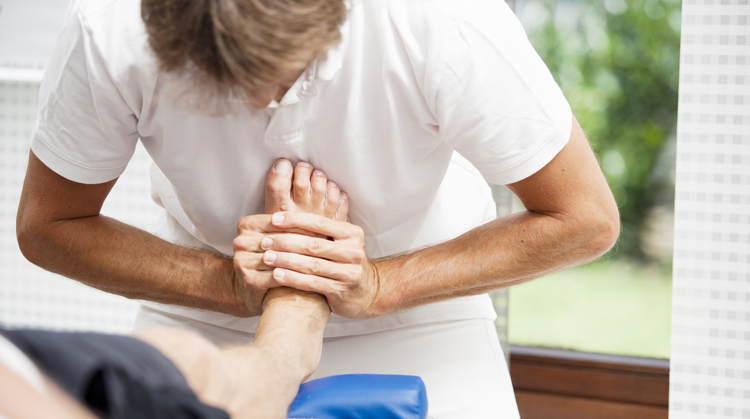 A physical therapist treats a patient with turf toe