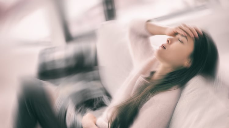 A women holds her head as the room spins around her.