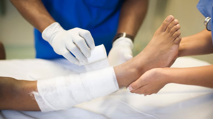 A physical therapist dresses a patient's wound.