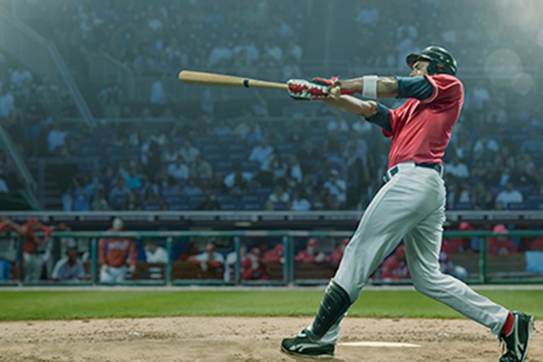 Pro baseball player swinging bat from home plate