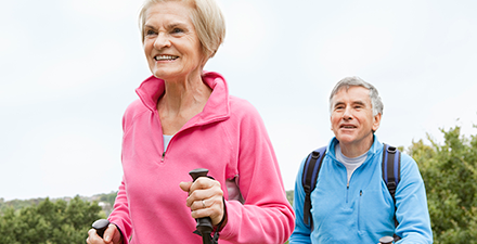 Older adults using walking sticks outdoors.