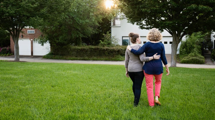 Two women, walking away, arm in arm.