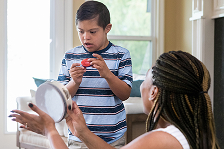 A boy with autism using musical instruments with his physical therapist.