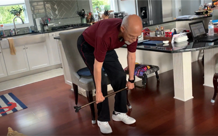 An older adult doing exercises with a cane.