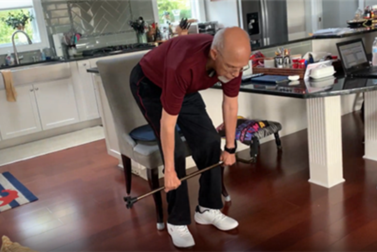 An older adult doing exercises with a cane.