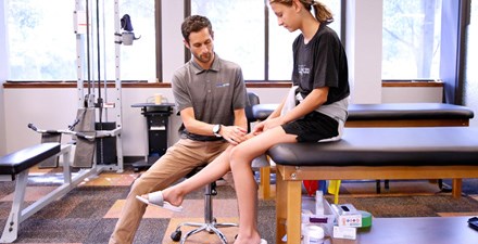 A teen with a physical therapist for treatment of knee pain.