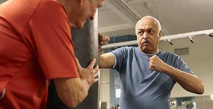 Two people in gym using a boxing bag