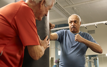 Two people in gym using a boxing bag