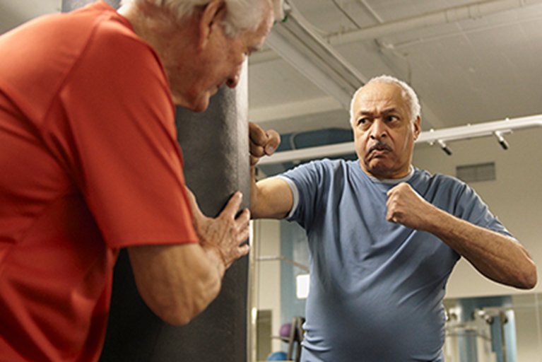 Two people in gym using a boxing bag