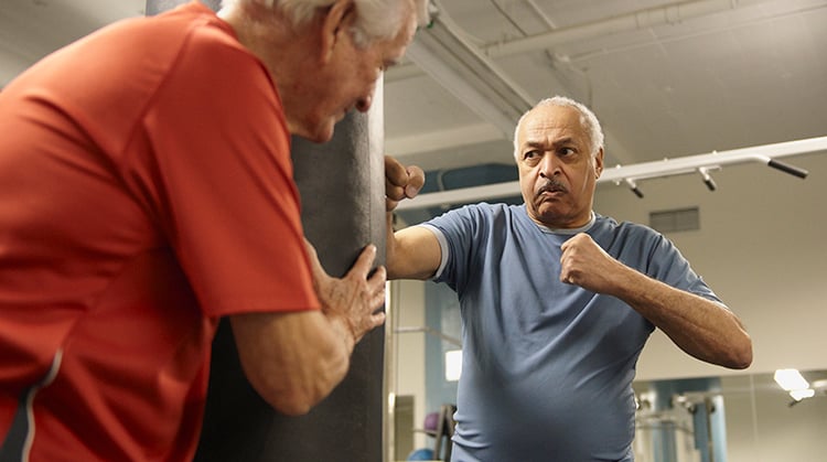 Two people in gym using a boxing bag