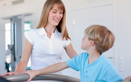 Physical therapist monitoring physical activity by a young boy.