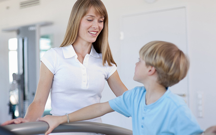 Physical therapist monitoring physical activity by a young boy.