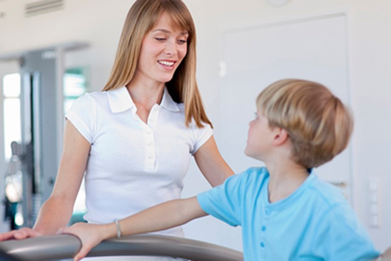 Physical therapist monitoring physical activity by a young boy.