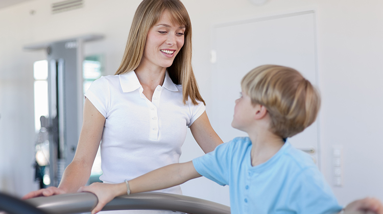 Physical therapist monitoring physical activity by a young boy.