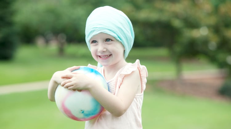 A child with cancer holding ball.